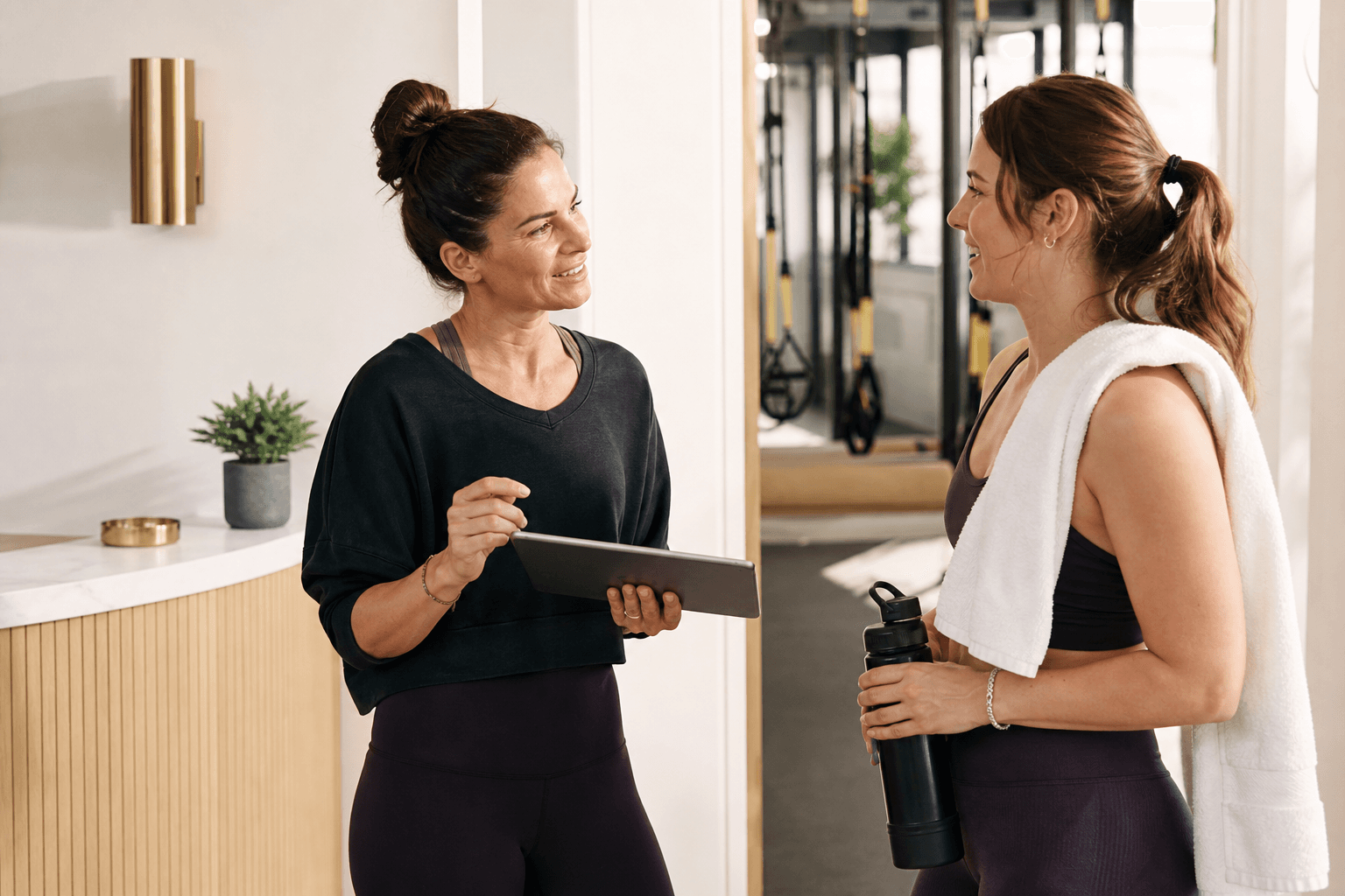 A studio operator speaking with a member after class while holding a tablet.